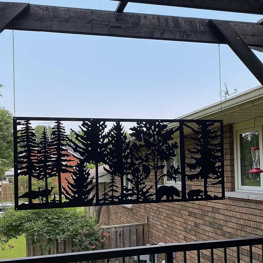 Metal forest scene wall art with black silhouettes of trees and animals against a red background, hanging from strings.